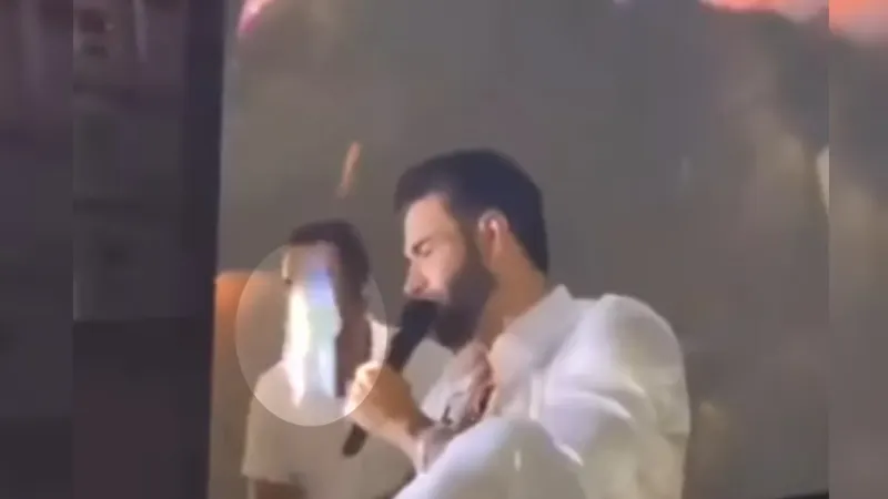 Gusttavo Lima no palco durante um show, com luzes e público ao fundo